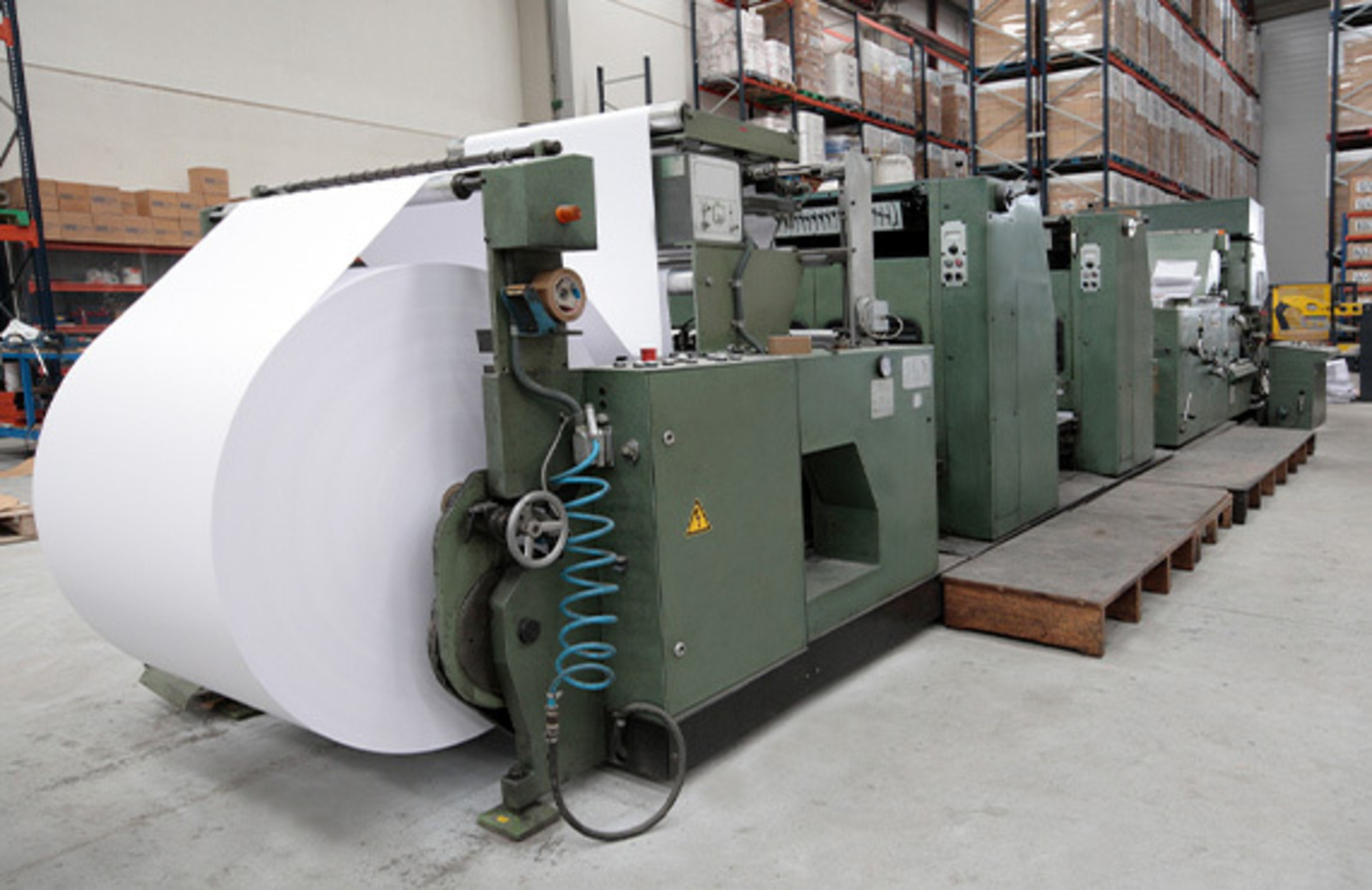Paper machine in a warehouse, utilized for machine condition monitoring in paper manufacturing.