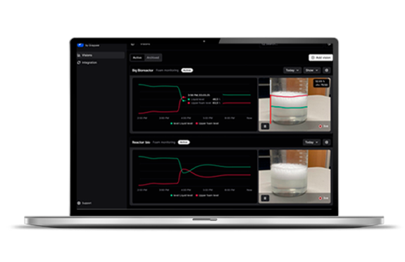 A laptop displaying a dashboard monitoring bioreactors with graphs and video feeds.