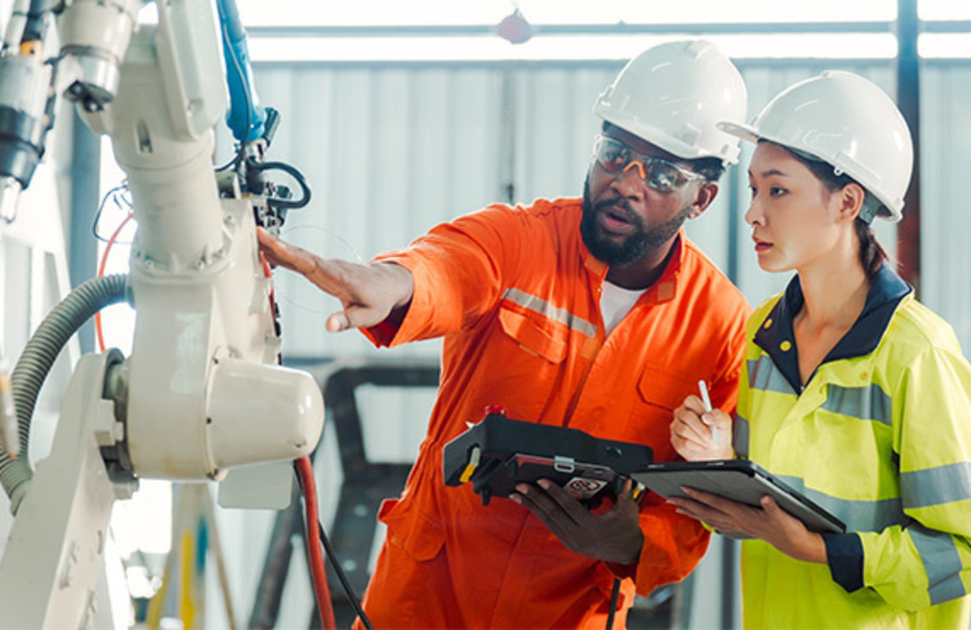 Two workers in hard hats inspecting a robot. Quality assurance in progress.