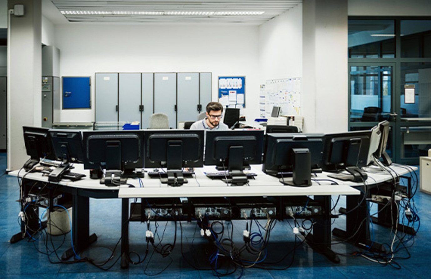 Factory employee in a control room, showcasing the role of cybersecurity in the convergence of OT/IT systems.
