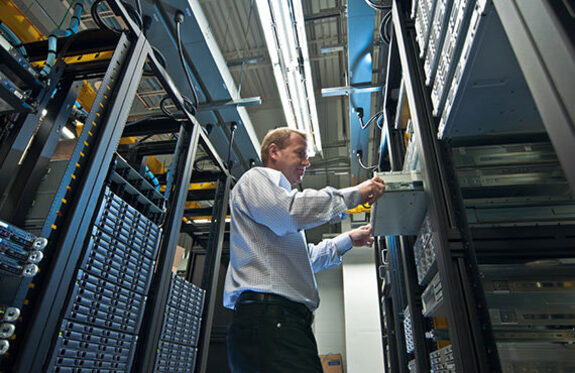 A technician working, handling and inspecting server equipment within a server rack