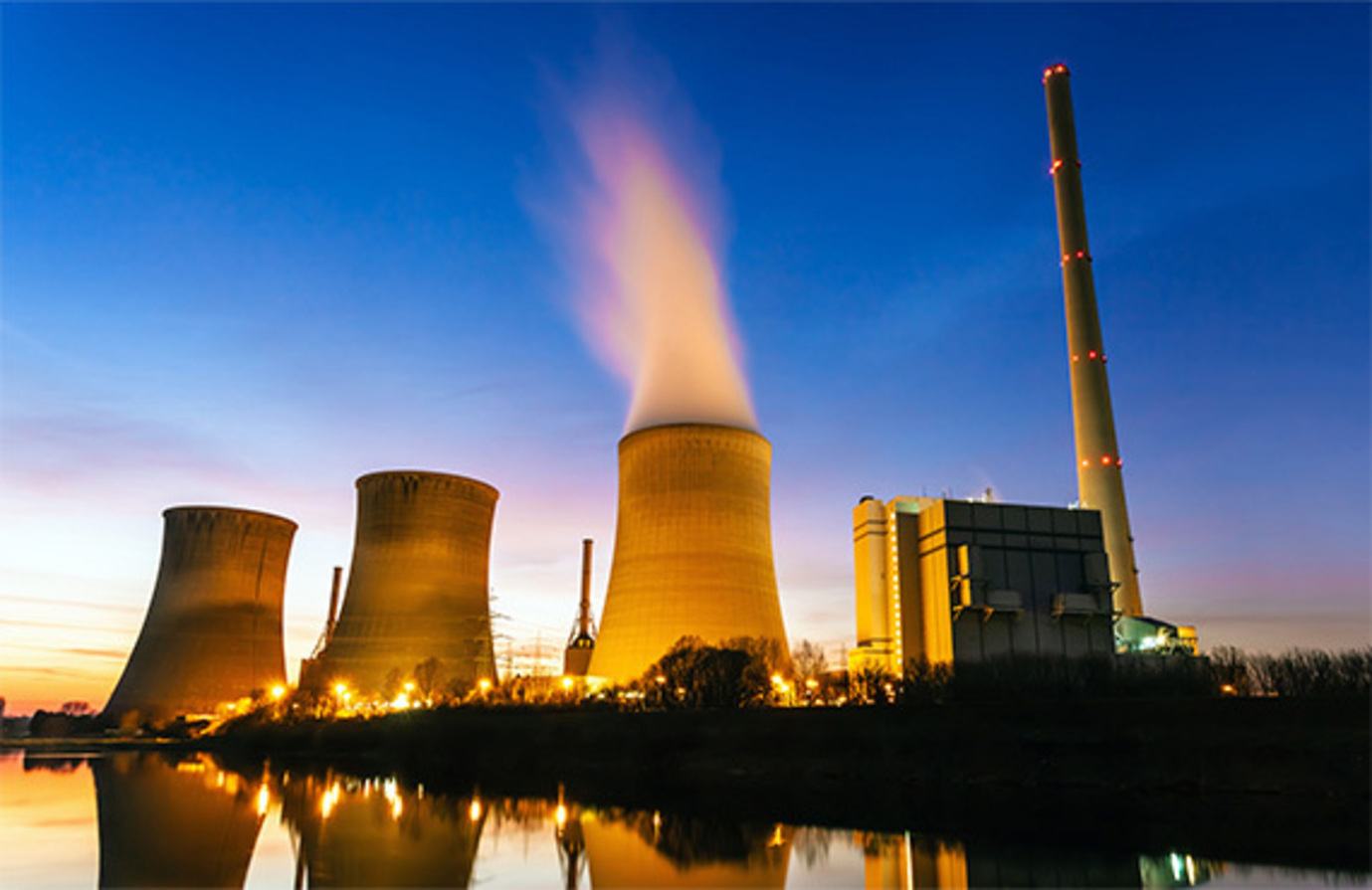 A large nuclear power plant at sunrise with steam coming from a cooling tower